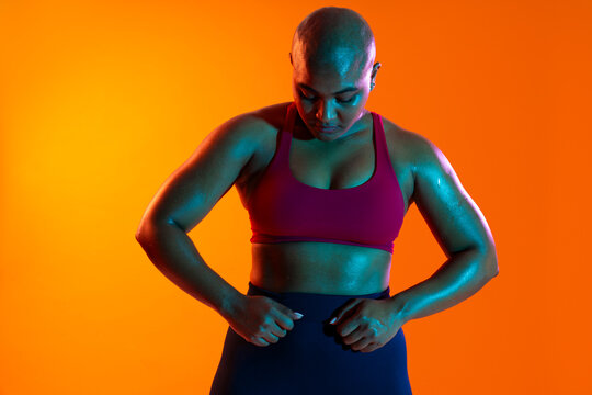 Bald athlete in sportswear focusing on fitness in a studio with orange background