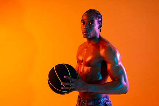 Athlete holding a basketball in a studio with colorful lighting