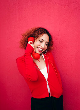 Redhead in red jacket smiling while talking on telephone outdoors