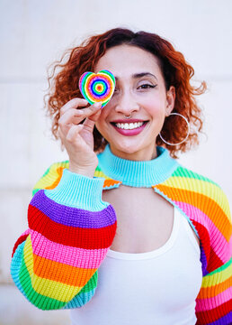 Smiling redhead with rainbow heart and colorful sweater showing joy