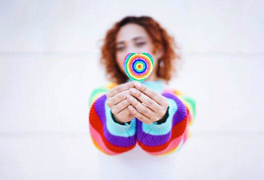 Redhead holding rainbow heart with colorful sweater showing love