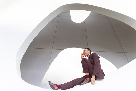Businessman in suit eating apple outdoors with positive mindset