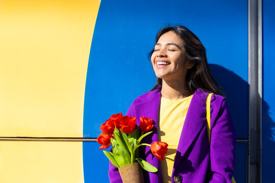 Smiling woman with tulip bouquet in colorful urban setting outdoors