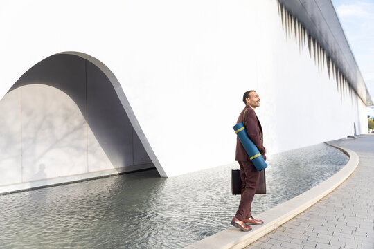 Businessman with yoga mat outdoors practicing corporate wellness