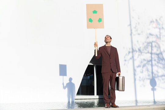 Businessman with sustainability sign standing by modern white building