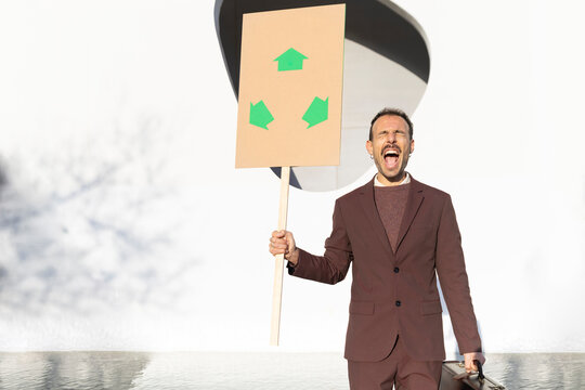 Businessman shouting for ecology holding sign outdoors in Barcelona