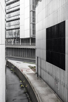 Modern concrete facade beside office towers forming an empty curved urban walkway in a business district with minimalist architecture and lines
