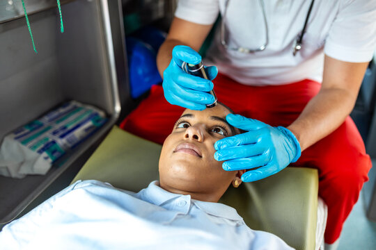 Doctor checking patient pupils with penlight in ambulance, Healthcare and Medicine concept. Professional paramedic performing neurological exam. Emergency medical service and first responder care.