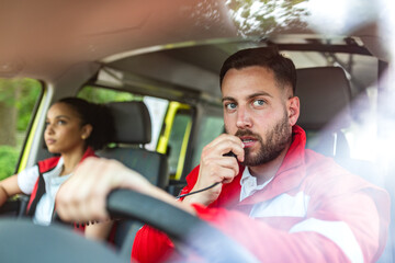Paramedic talking on radio walkie talkie while driving ambulance, Healthcare and Medicine concept. Emergency medical team responding to call. Professional first responder in uniform inside vehicle. © Graphicroyalty