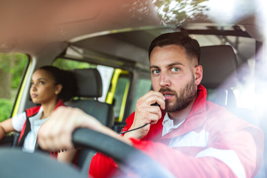 Paramedic talking on radio walkie talkie while driving ambulance, Healthcare and Medicine concept. Emergency medical team responding to call. Professional first responder in uniform inside vehicle.