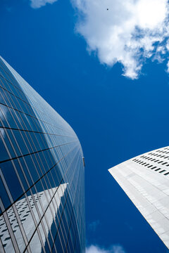 Modern glass skyscraper tower in urban architecture seen from upward perspective with sky and fast cloud forming dramatic lines for clean corporate background