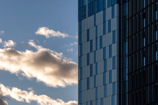 Glass facade architecture of modern office building with urban grid lines against sky as drifting cloud shapes a clean corporate background for design use