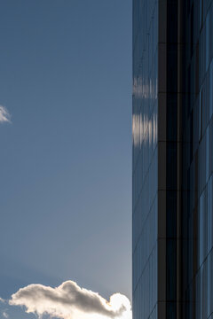 Modern vertical building facade in glass architecture set below wide sky where soft cloud leaves urban copyspace and minimal style for branding background