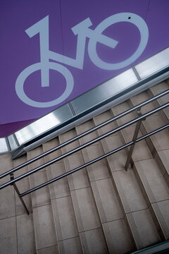 Minimal bicycle symbol sign on purple stairs in an urban space with direction for transportation and graphic design style for wayfinding concept