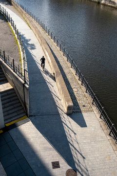 Bicycle cyclist on a river walkway in urban sunlight with shadows showing transportation perspective in berlin along a calm waterfront route
