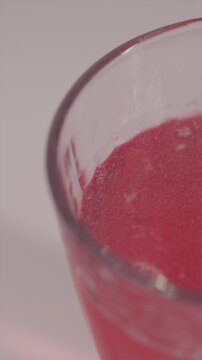 Macro shot of red bubbles rising in glass of vitamin drink