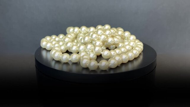 Collar de perlas girando 360 grados sobre base giratoria negra