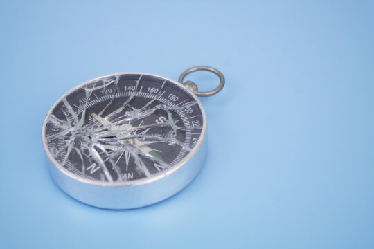 Broken compass on blue background. Copy space for text.