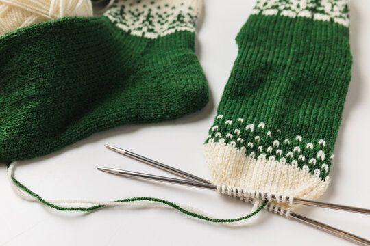 Macro shot of knitting needles and wool yarn during sock making process.
