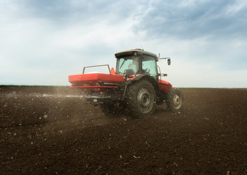 Tractor fertilizing field, Tractor spreading artificial fertilizers.