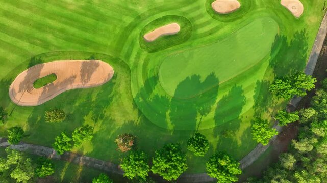 Aerial drone view of a lush golf course with sand bunkers and winding paths, highlighting sustainable landscape design and eco-friendly outdoor recreation in modern urban environments.
