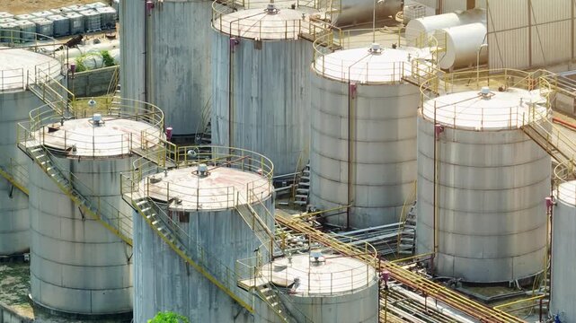 Aerial view of oil refinery facilities with cylindrical tanks and metal walkways, symbolizing critical fuel production as global markets respond to supply disruptions and sustainability pressures.
