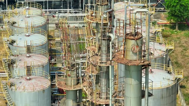 High-angle drone shot of refinery towers and storage tanks, illustrating petroleum refining operations that convert crude oil into fuels driving global energy consumption and economic activity.
