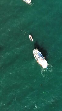 Drone shot of boats floating on clear turquoise water near Koroni, Greece. Peaceful maritime scene with vibrant colors and calm sea.