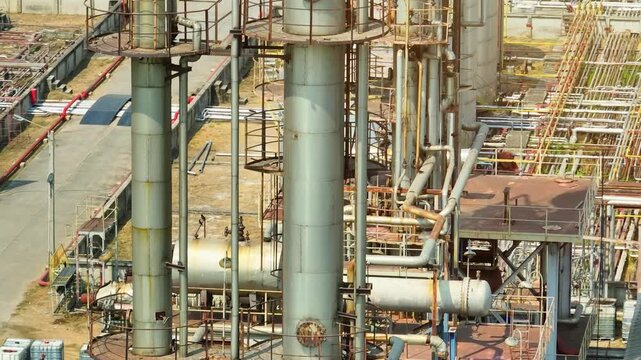 Drone perspective of refinery columns and industrial piping systems, highlighting petroleum processing infrastructure amid fluctuating oil prices and ongoing global energy security concerns.
