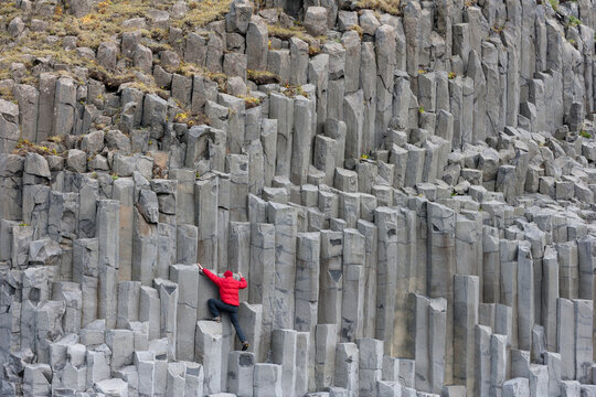 Man climbing basalt columns at Reynisfjara beach, Iceland
