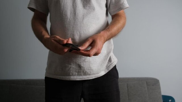Male hands carefully wrapping a black charging cable for storage in a living room