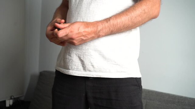 Man's hands neatly wrapping a black USB cable for storage in his apartment living room