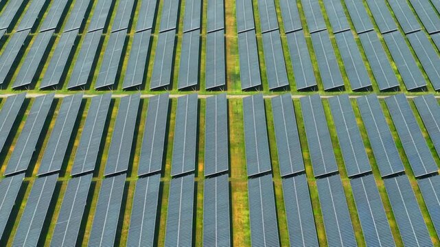High-angle drone shot of solar panel rows and service paths, illustrating large-scale green energy infrastructure driving the shift away from fossil fuels toward sustainable power.
