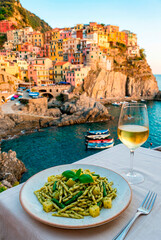 Obraz premium Pasta and wine with a picturesque Italian coastal village backdrop