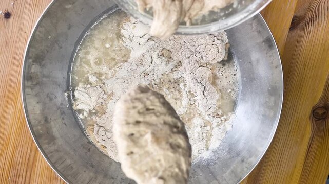 Sourdough starter being added to flour and water mixture in bowl