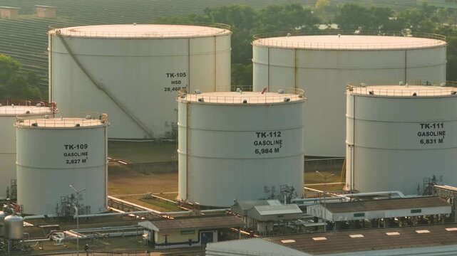 Drone perspective of large oil tanks and industrial infrastructure, highlighting fuel storage systems supporting energy supply amid fluctuating oil prices and global demand shifts.
