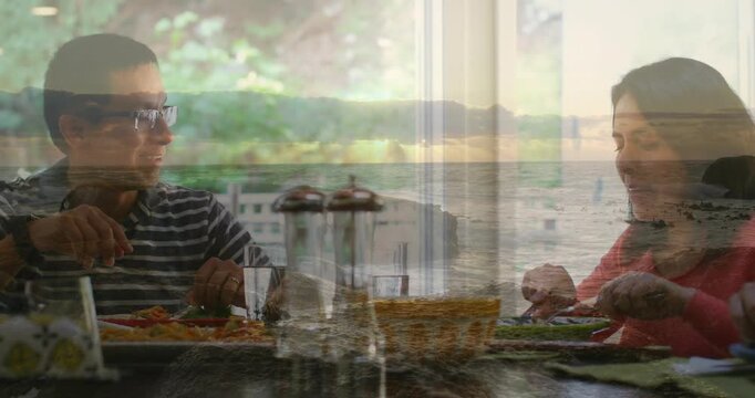 Man looking up then reaching to share bread, couple cutting food while seascape overlay shimmering