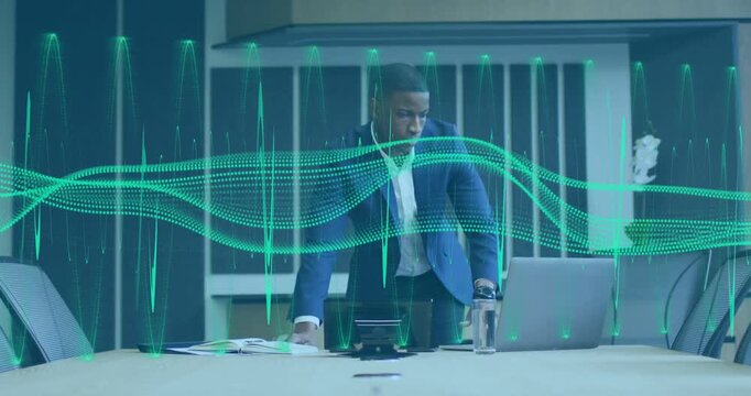 Businessman leaning, standing on getting audio feed monitoring laptop with green waveform overlay