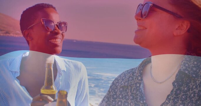 Smiling short hair woman raising bottle toasting friend at coastal overlook beer bottles color band