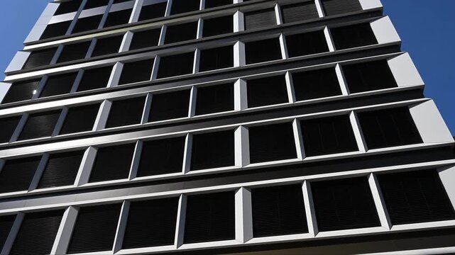 Modern office building exterior with white grid and dark louvers