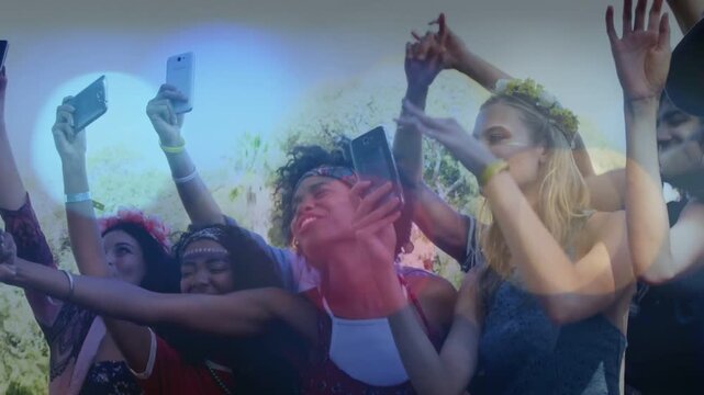 Group raising smartphones as music starting, swaying and filming show while lens flare sweeping