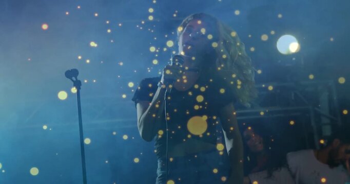 Vertical video: Lead singer flipping head and drawing mic closer, singing during gig amid gold dots