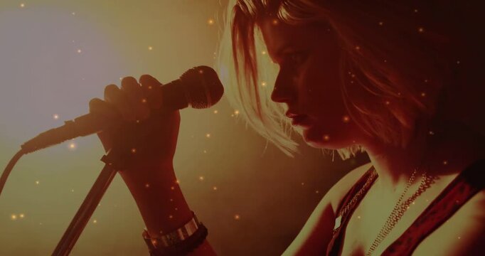 Vertical video: Reaching mic stand, singer singing close-up on stage in tank top, amber-lit haze