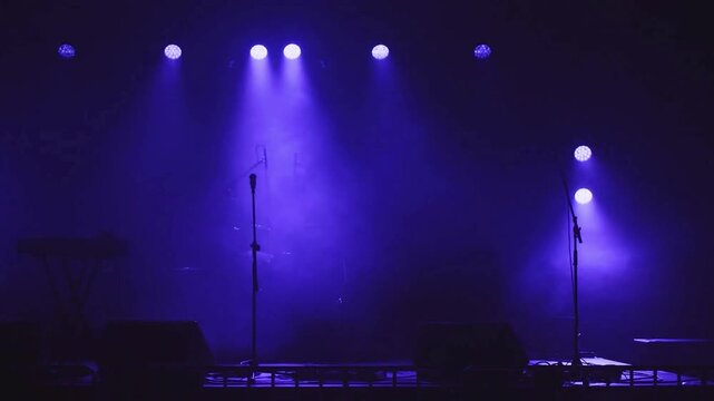 Stage lighting with purple beams and smoke during concert preparation.