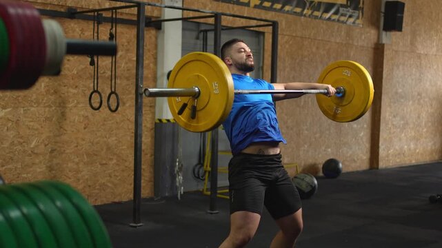 Strong man performing a barbell snatch exercise in the gym
