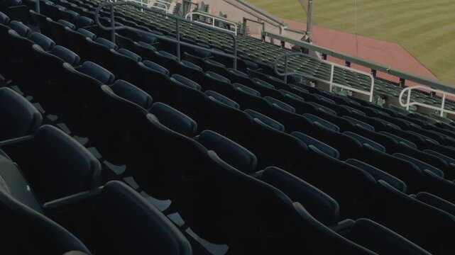 Slow steady left to right pan across empty stadium seats with outfield grass beyond.
