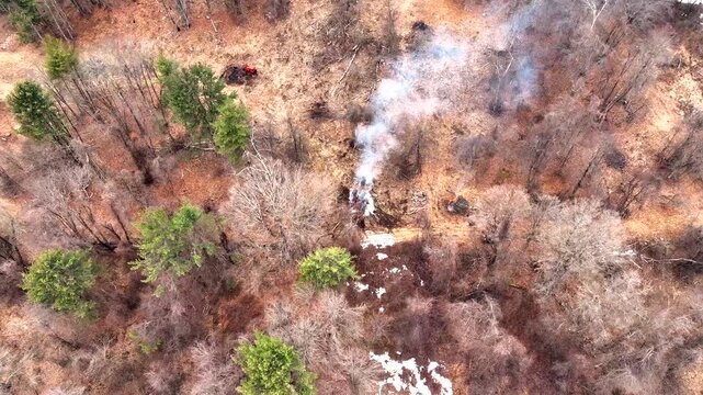 Aerial View Of Forest Landscape With White Smoke Rising From Controlled Burn In Winter. orbiting shot