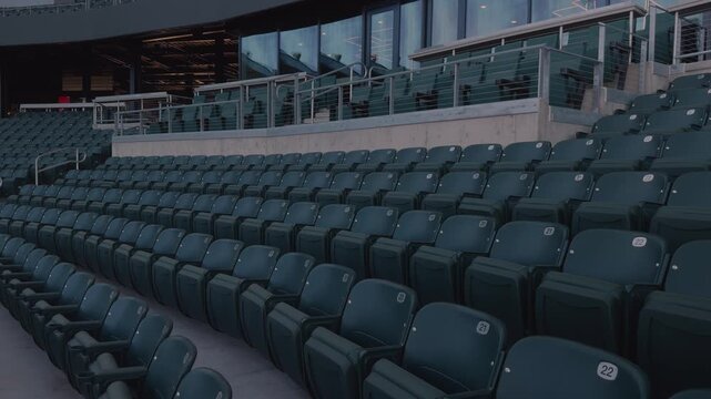 Slow steady pan across empty stadium seating rows, railings, and concourse under daylight