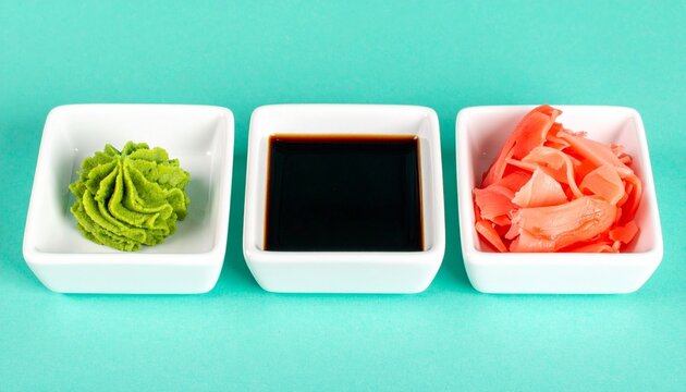 Three bowls with wasabi soy sauce pickled ginger turquoise background