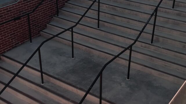 Slow steady left to right glide over wide concrete steps and railings beside brick wall